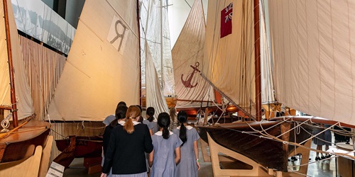 Students walking through museum gallery with ships